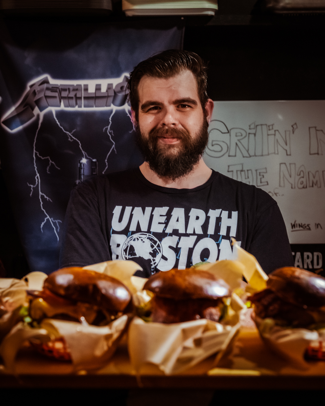 Travis behind a counter full of burgers